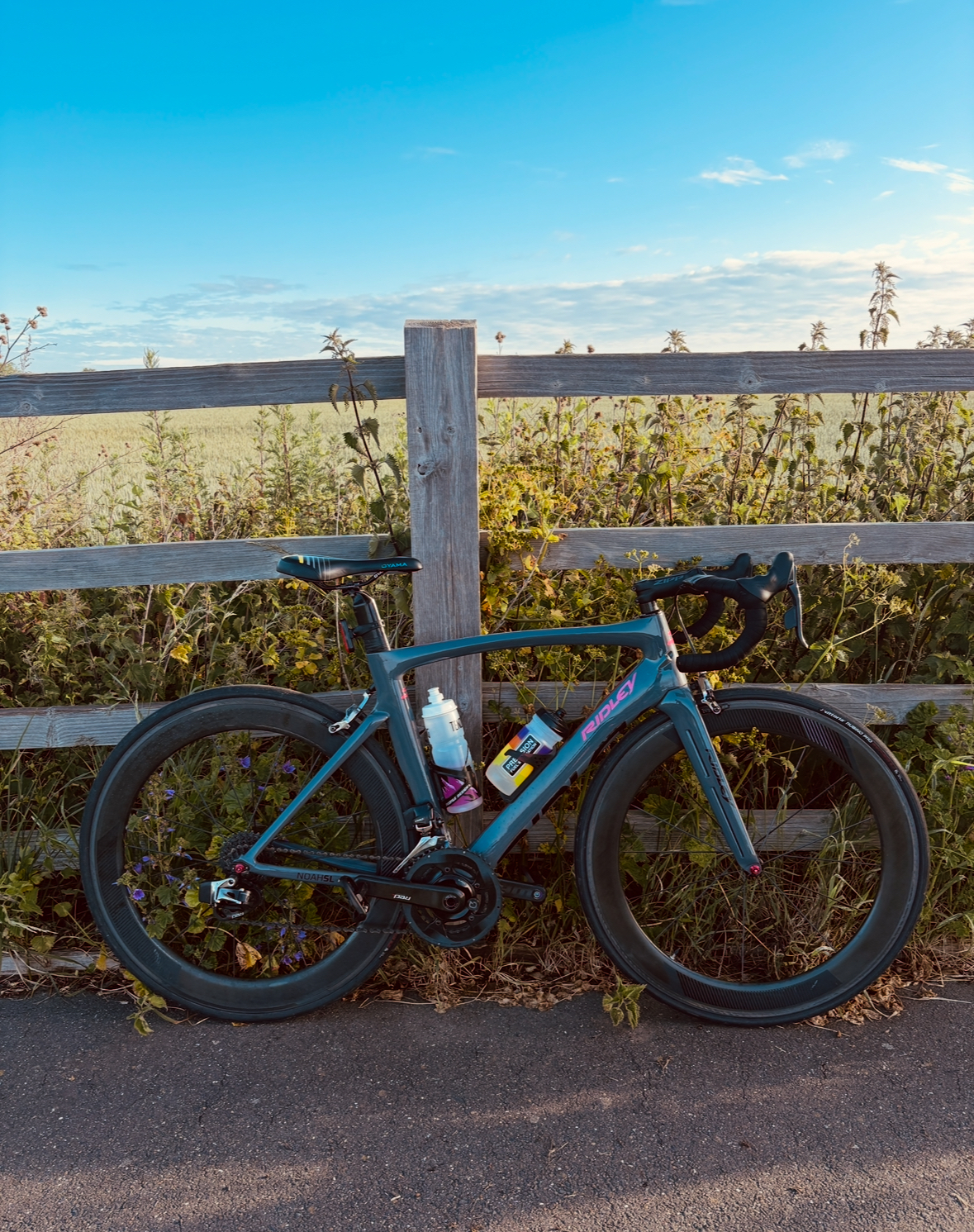 Road bike leaning against a fence beside a field at sunrise